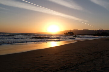 Naklejka na ściany i meble Sunset at Santa Monica Beach, California. The golden color of the sand.