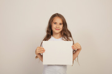 Fototapeta premium a beautiful sweet happy girl with long hair in a white T-shirt is holding a white sheet in her hands