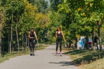 Fototapeta na wymiar Sporty girls roller skating in park on inline skates. Female bonding.