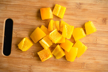 Yellow Bell Pepper Sliced into Large Chunks: Sweet yellow pepper cut into large pieces on a bamboo cutting board
