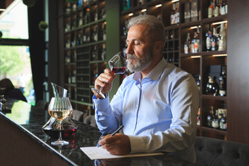 A senior sommelier is tasting red wine.