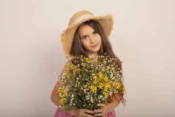 portrait of a beautiful long-haired girl in a straw hat with wild autumn flowers in her hands
