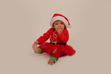 beautiful little girl in a Christmas costume and santa hat on a white background