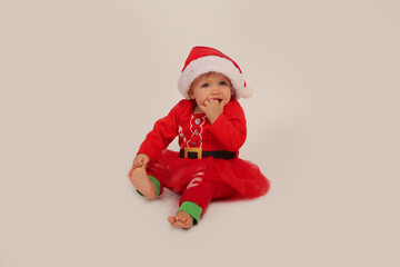 beautiful little girl in a Christmas costume and santa hat on a white background
