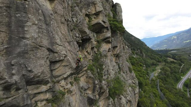 Strong muscular man rock climber, rappels down and removes the quickdraw on the hooks. successful completion of the climbing route. Outdoor rock climbing and active lifestyle concept, drone shot