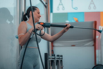 Chica joven entusiasmada trabajando el el servicio de autolavado mientras lava a presión con la...