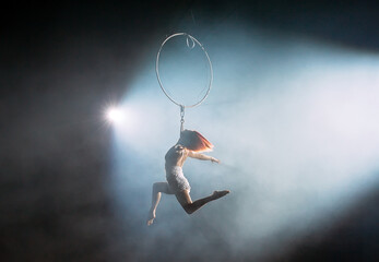 Aerial acrobat in the ring. A young girl performs the acrobatic elements in the air ring.