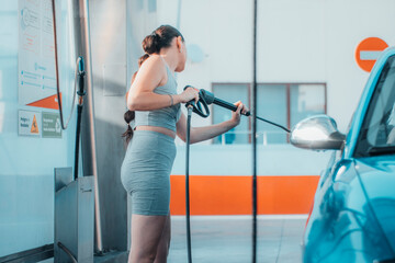 Mujer joven empleada trabajadora del lavadero de coches realizando una limpieza del vehículo de su...