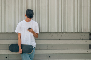 teenage boy with mobile phone and skateboard on the street