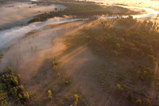 Mist covers the river, trees, and land at dawn. Autumn photos of fog taken with drone