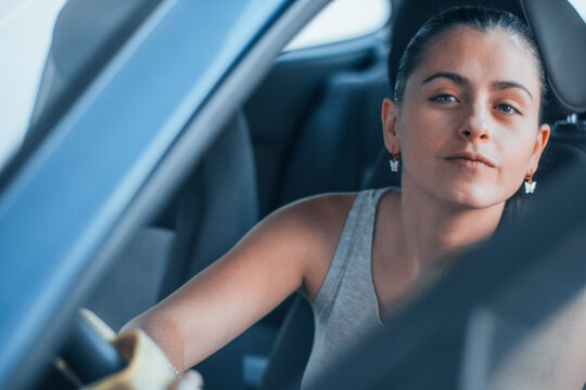Chica joven morena de piel blanca limpiando el volante del interior del coche en un centro de lavado junto a una gasolinera