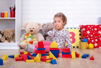 Cute little girl of 2 years old is playing with wooden cubes , Toy blocks pyramid
