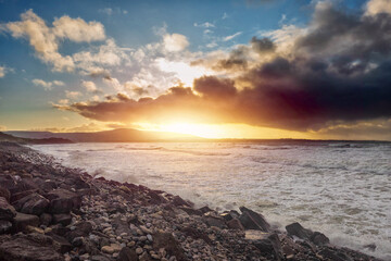 Fototapeta premium Strandhill beach at sunset. County Sligo, Ireland. Cool and warm light. Cloudy sky. Dramatic sky. Nobody. Ocean waves rushing towards the coast.