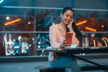Muchacha joven posando y sonriendo para un selfie sentada en una mesa de un picnic junto a un...