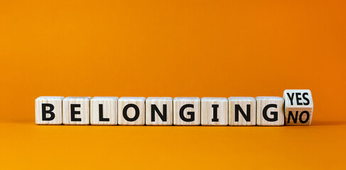 Belonging yes or no symbol. Turned a wooden cube and changed words 'belonging no' to 'belonging yes'. Beautiful orange background. Business and belonging yes or no concept, copy space.