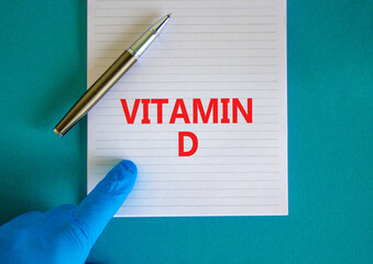 Vitamin D symbol. White note with words Vitamin D, beautiful blue background, doctor hand in blu glove and metallic pen. Medical, vitamin D concept.