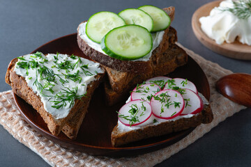 Sandwiches with soft cheese radish and cucumber on a wooden cutting Board. Healthy breakfast
