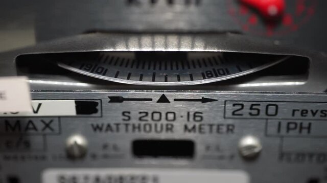 Macro close-up of a domestic electric meter and slow turning measuring dial. Concept for energy, utility bills, price rise, meter reading, inflation and electricity supplier. Static shot.