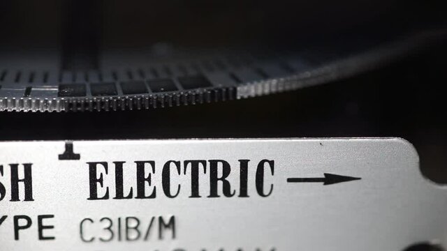 Macro close-up of electric meter dial edge, slow spinning measuring dial. Concept for energy supplier, bills, price rise, inflation and wholesale.