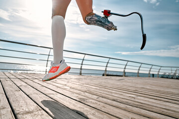 Never give up. Cropped photo of a disabled woman with a prosthetic leg in sportswear jumping on the bridge.