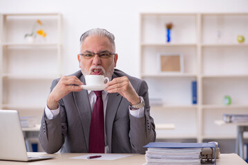 Old male employee drinking coffee during break