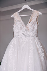 Fototapeta na wymiar beautiful white dress hanging on a hanger. Wedding preparations. Morning of the bride.