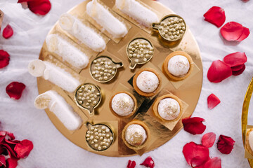 Candy bar: white muffins with sprinkles on a white plate and a vintage gold plate. Sweet table for an adult party