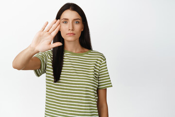 Stop it. Serious brunette woman stopping, showing block taboo gesture, saying no, standing in...