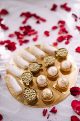 candy bar to celebrate the holiday. Sweet buffet for birthday or wedding. Assortment of desserts on the table on a golden plate with rose petals
