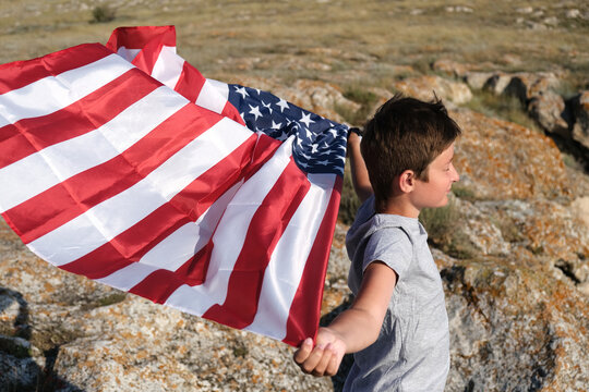 A boy holding waving US flag, beeng a patriot concept