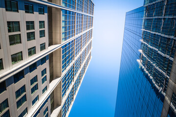 Fototapeta premium Abstract geometry and shapes of modern buildings in Boston with glowing sun rays from the blue sky illuminating the walls, low angle view