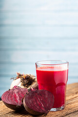 Red beet juice in a glass cup on the wooden table.