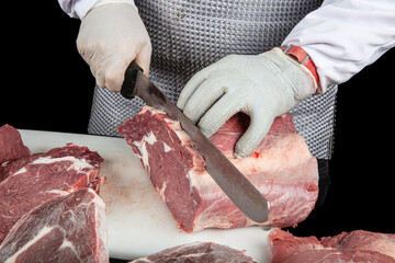 Close up of minced meat pieces and butcher's male hands in special gloves cutting with knife. Meat...