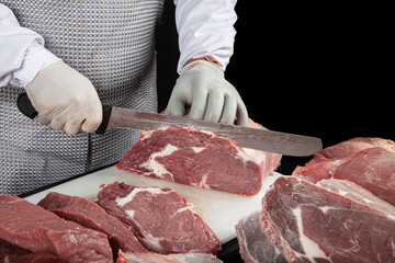 Close up of minced meat pieces and butcher's male hands in special gloves cutting with knife. Meat...