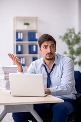Young male employee and too much work in the office