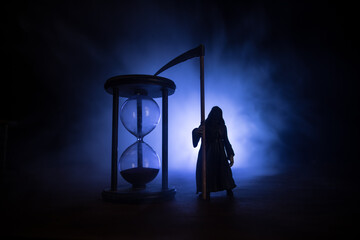 Time concept. Silhouette of Hourglass clock and old vintage wood clock with arrow and smoke on dark...