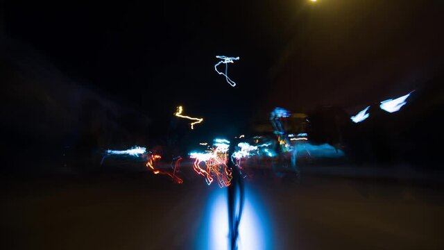 Man riding electric scooter over night streets of illuminated town fast timelapse. Hyperlapse of driver rolling eco electrobike on high speed from first view. Theme of motorcycles rolling at city.