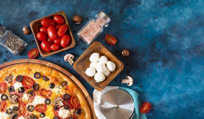 Original composition - pizza edge, ingredients and knife. Dark blue background. Low angle view....