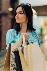 young woman, shopping mall with shopping bags choosing clothes in mall or clothing store