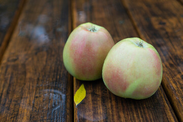 Autumn apples in the rain. Organic apples on the wooden table. Raindrops on green apples. Northern spy