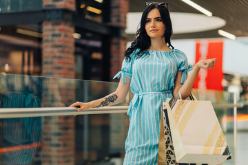 young woman, shopping mall with shopping bags choosing clothes in mall or clothing store
