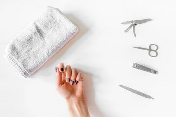 Closeup of woman hand with polished nails and manicure instruments. caucasian woman receiving french manicure at home or at nail salon. manicure, selfcare, beauty procedures yourself