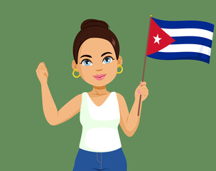 Beautiful happy smiling Hispanic Cuban woman with bun hairstyle holding Cuba flag making positive fist up hand gesture