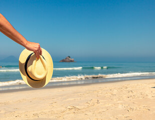 Fototapeta na wymiar female hand holding the hat on the beach