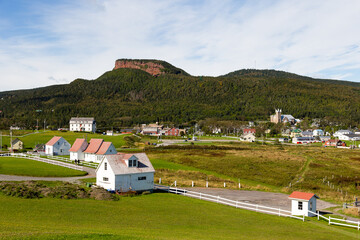 Selective focus high angle view of historic houses on Mount Joli, with scattering of houses and church in the background seen during a beautiful summer day, Percé, Quebec, Canada