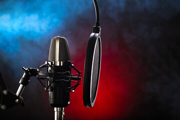 Studio microphone and pop filter on red-blue background. Minimalism. There are no people in the photo. Close-up. Recording studio, vocals. music, concert, purity of sound, debate. - 458148862