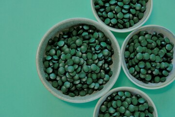 Spirulina algae dry tablets. Spirulina pills in cups on a green background. Vegetarian omega three. source of amino acids and omega 3.Omega three alternative source. Super food. 