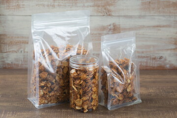 Caramel cornflakes in plastic bag package on wooden table.