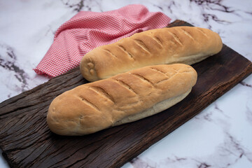 Whole and sliced long homemade bread on natural and fresh wooden board