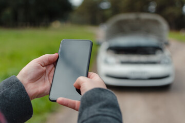 Close-up of a woman's hands using a cell phone to call for help with her broken car